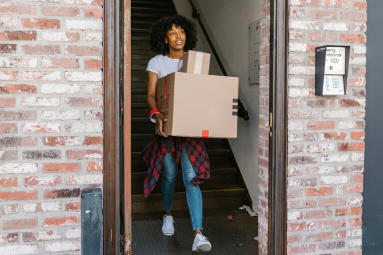 A woman is carrying carton outside her old apartment in the concept of moving to West London.