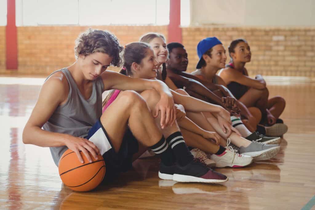 High school kids sitting on the basketball court floor