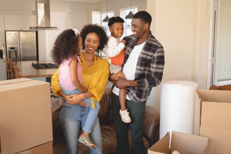 A young family is inside their new house and surrounded by cartons in the concept of 'how to save money when moving to West London'.