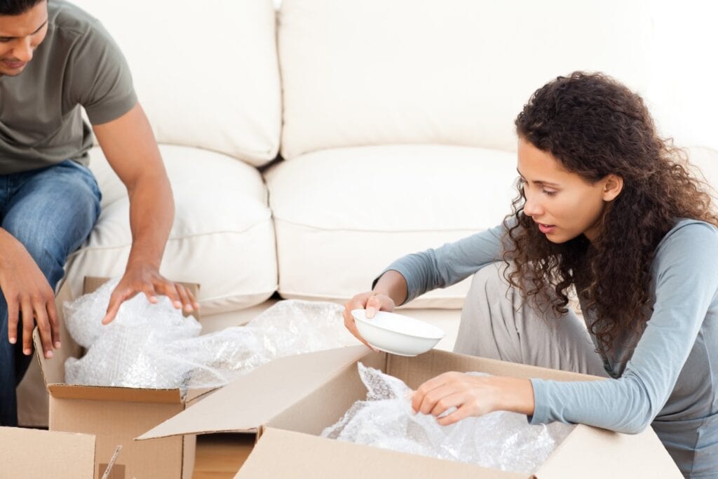 A couple is packing household items into boxes