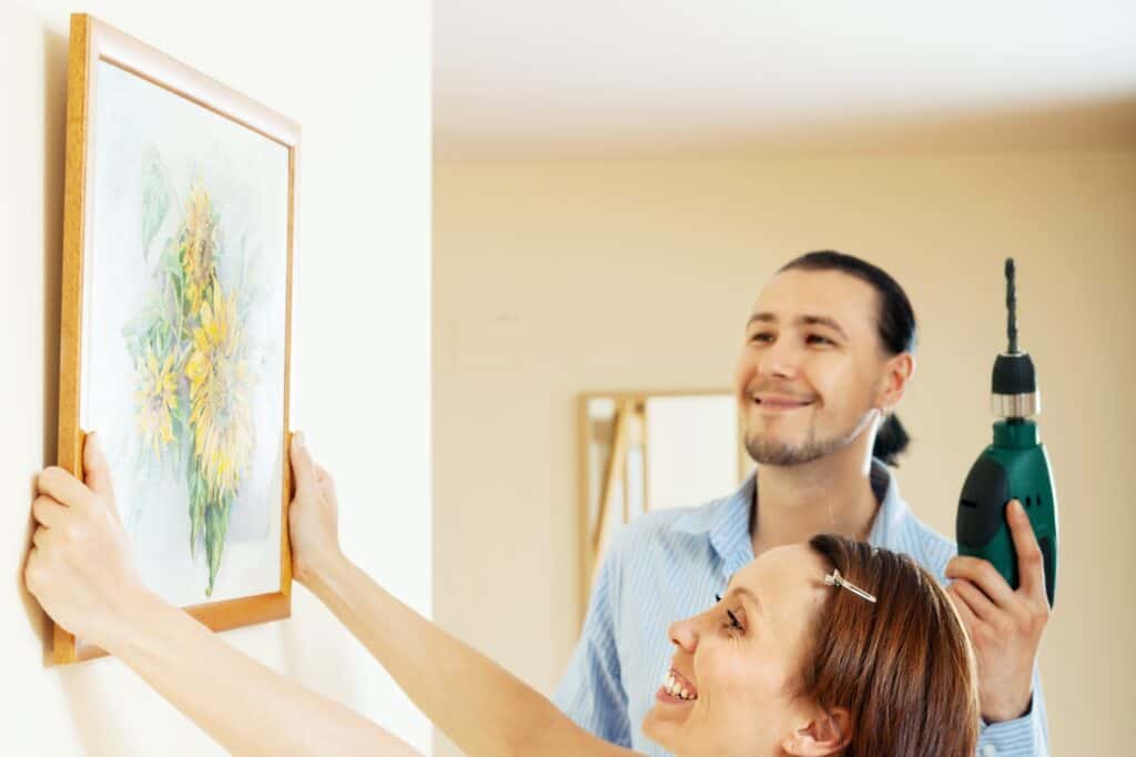 A smiling couple personalising their new flat with a picture frame