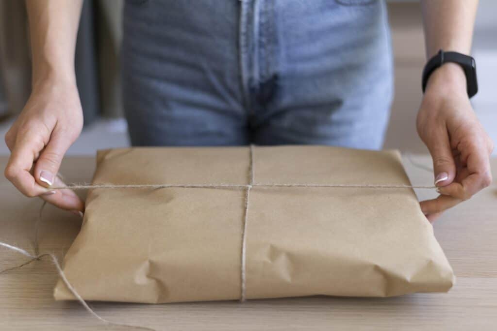 Cropped image of a woman wrapped a gift by repurposing packing paper