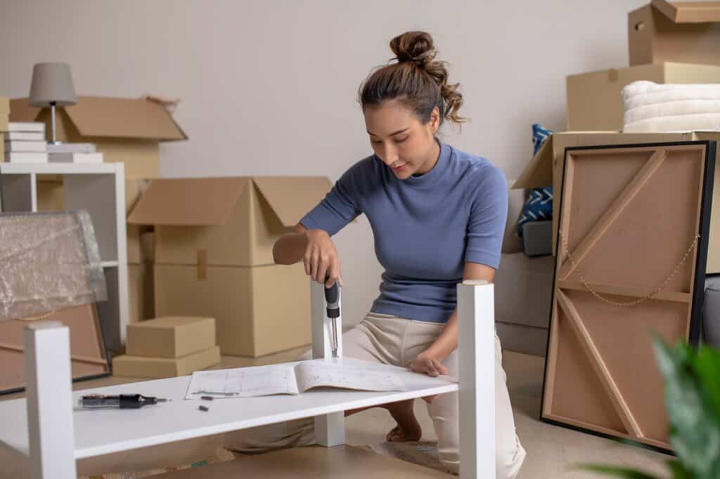 A young woman assembling a table after the move in the concept of 'How to Pack and Unpack for a Home Removal Efficiently'.