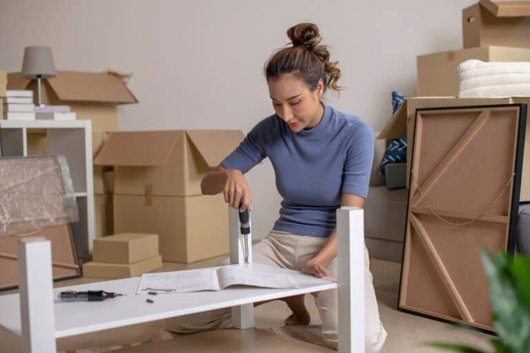 A young woman assembling a table after the move in the concept of 'How to Pack and Unpack for a Home Removal Efficiently'.