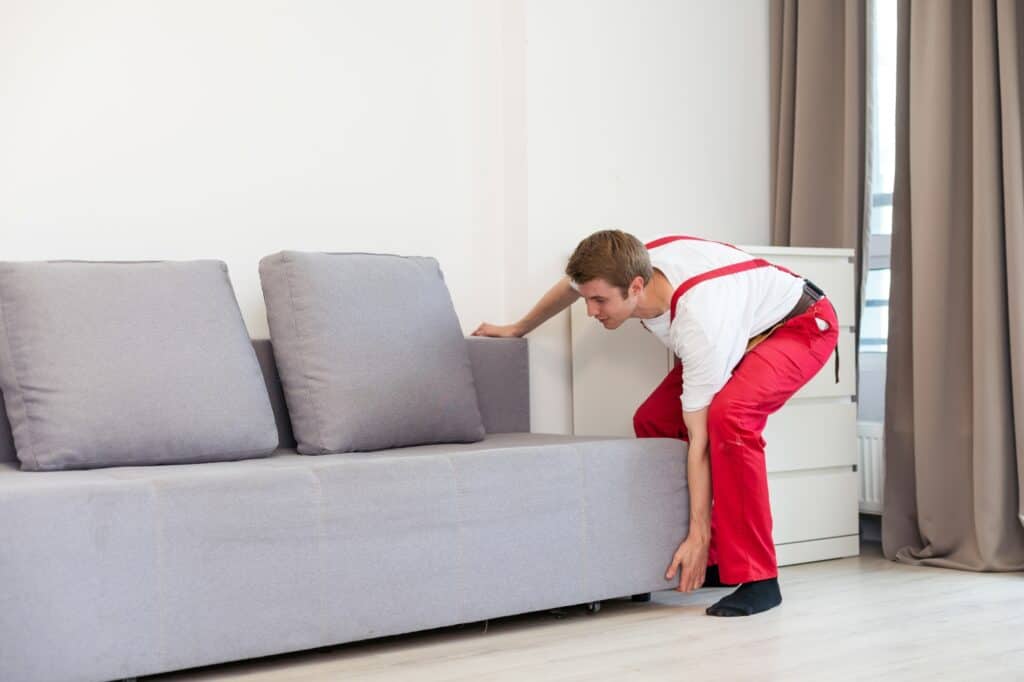 A professional mover placing the sofa into the new flat in the concept of 'How to Choose the Best Home Removals Company'.